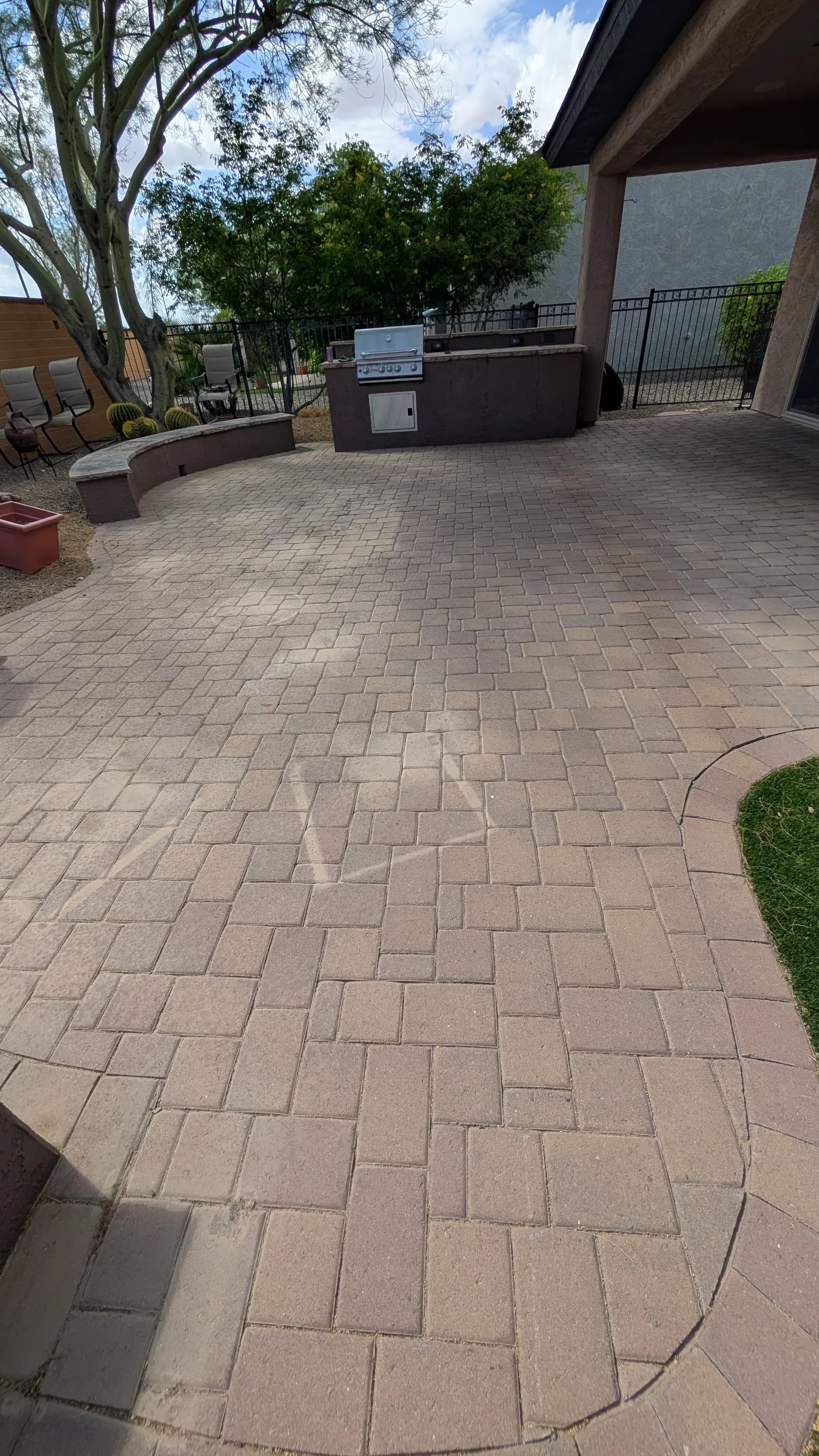 Paver patio with outdoor grill, surrounded by landscaping and seating area.