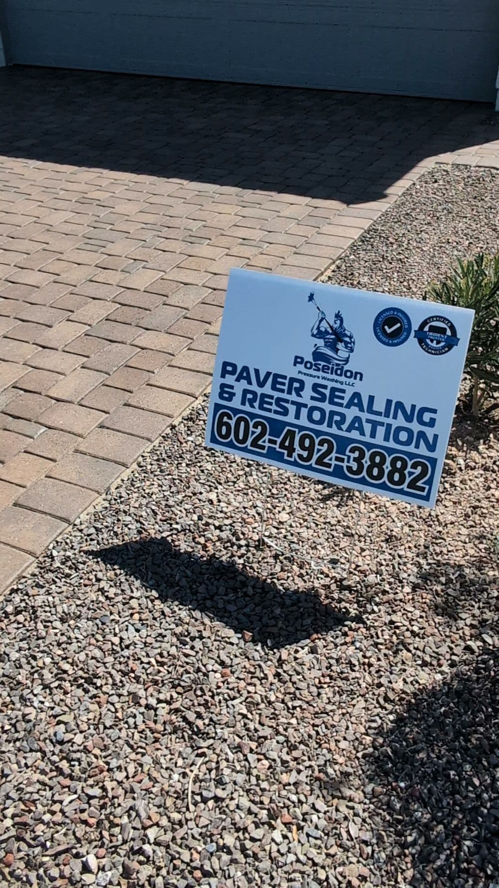 Poseidon Paver Sealing & Restoration sign with contact information displayed on paving stones.