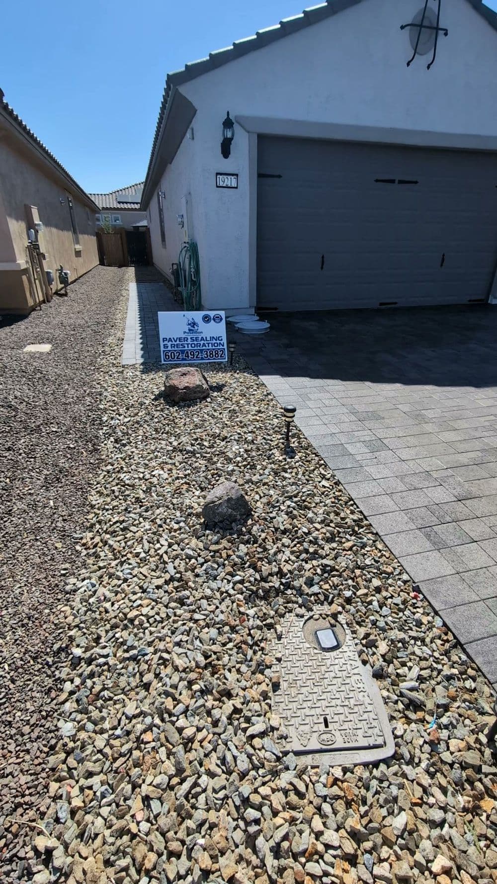 Residential property with gravel landscaping, garage, and service sign near the entrance.