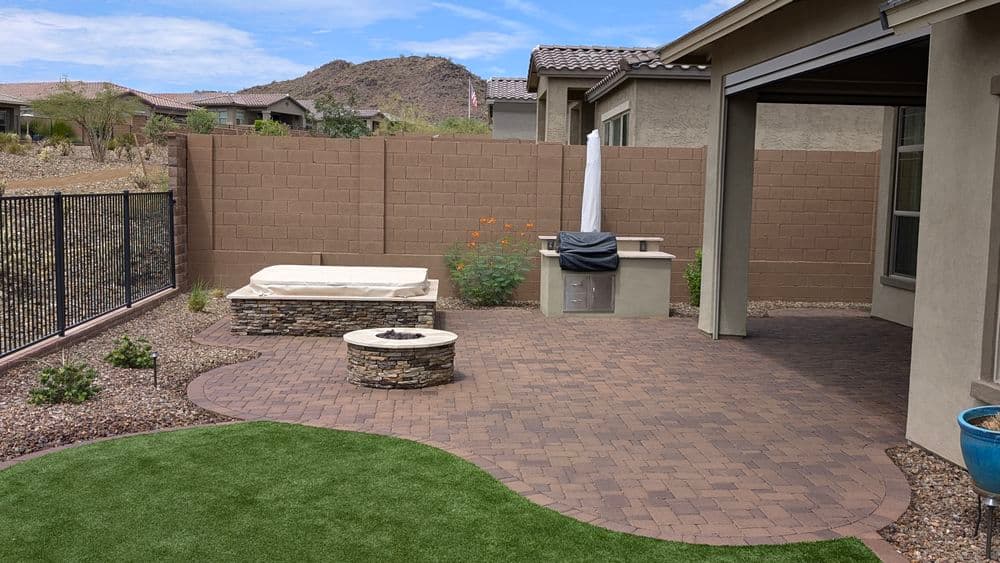 Stylish backyard patio with fire pit, spa, and landscaping in desert setting.