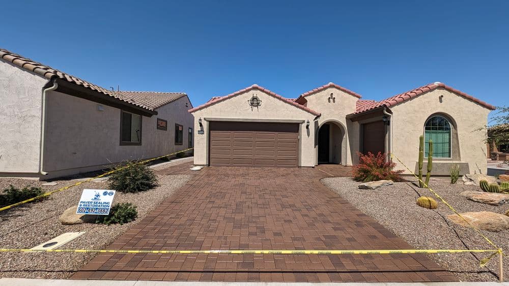 Single-story desert home with tan exterior, red tile roof, and front paver driveway.