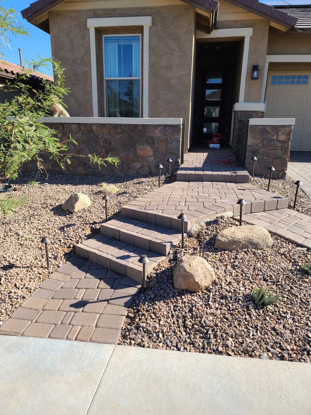 Welcoming home entrance with stone pathway, decorative rocks, and LED lights.