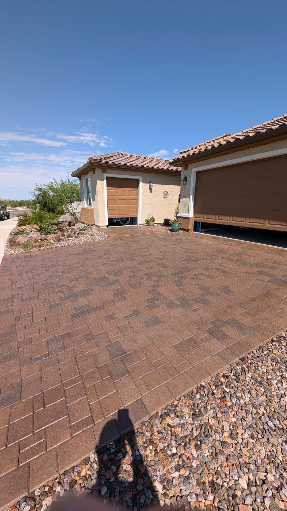 Paved driveway leading to a home with a garage and landscaped stone border.