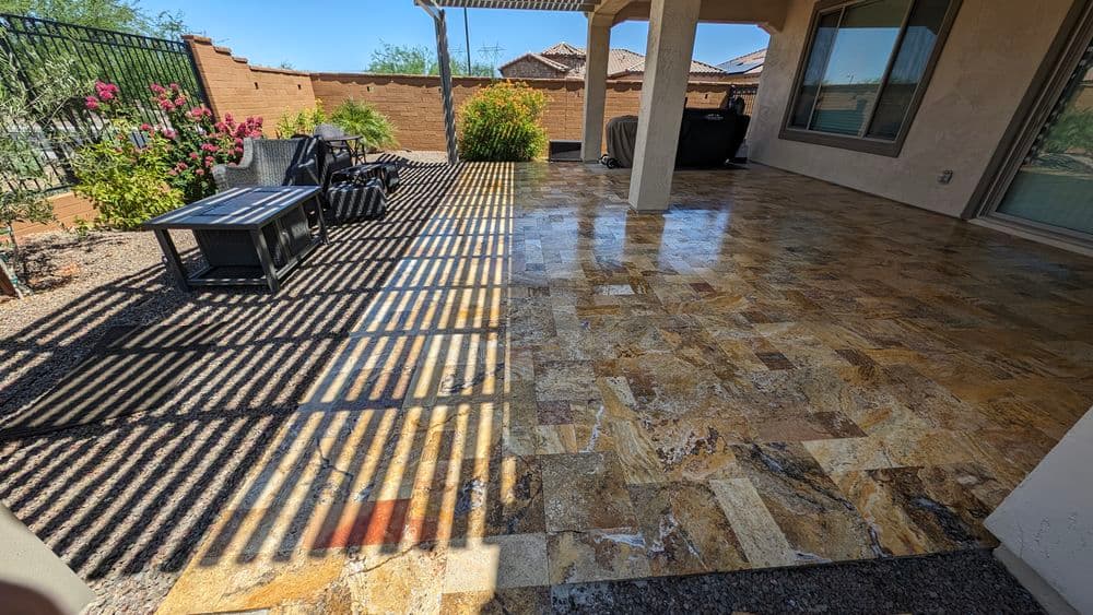 Elegant outdoor patio with polished stone flooring, shaded seating area, and vibrant greenery.