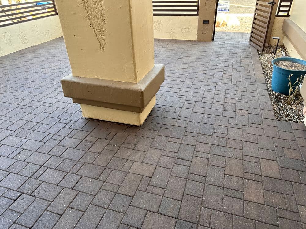 Paved outdoor patio with a column and potted plant, showcasing clean, modern design.