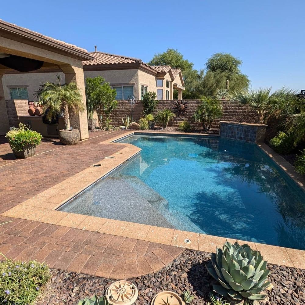 Backyard oasis featuring a sparkling pool, lush landscaping, and modern home exterior.