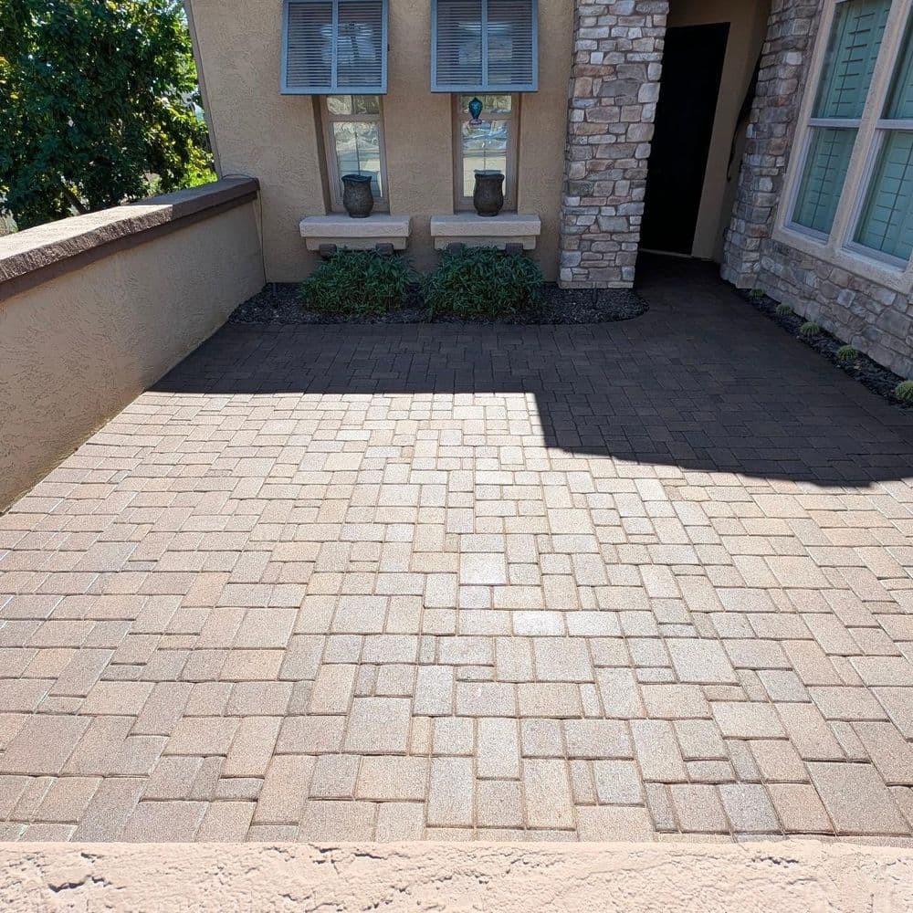 Paver stone driveway with light and shadow, leading to a home's entrance.