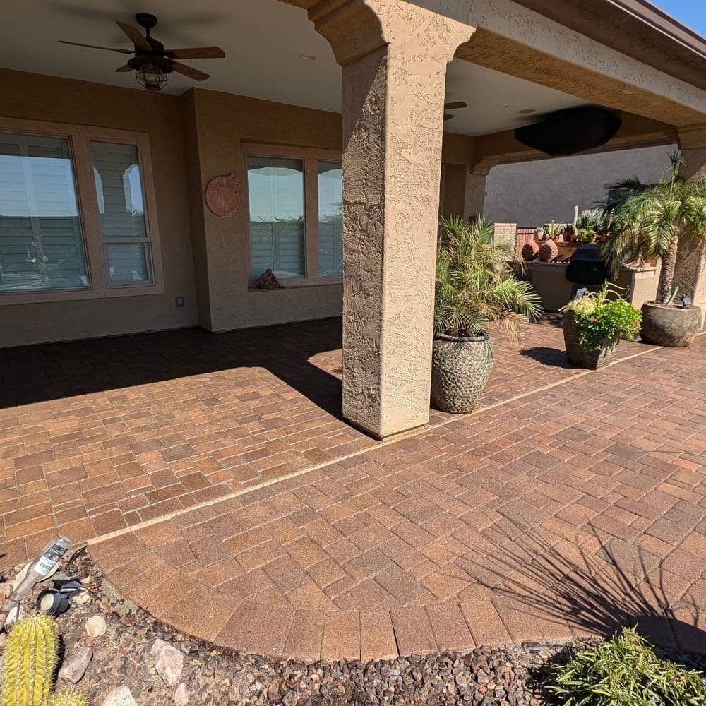 Paved patio with potted plants and rustic decor under a shaded porch. Desert landscape.
