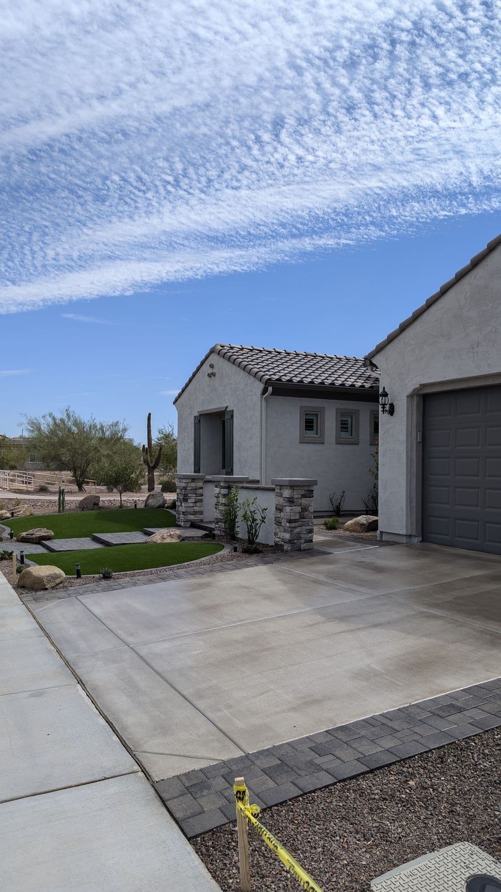 Newly built desert home with modern architecture, stone accents, and landscaped yard.