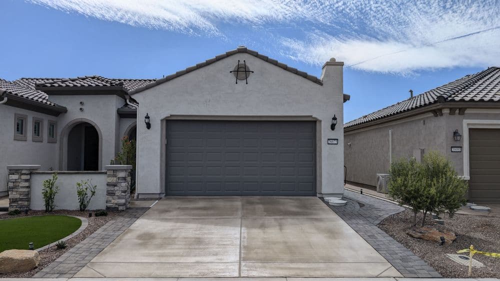 Modern single-family home with a gray garage door and stone accents, situated in a sunny neighborhood.